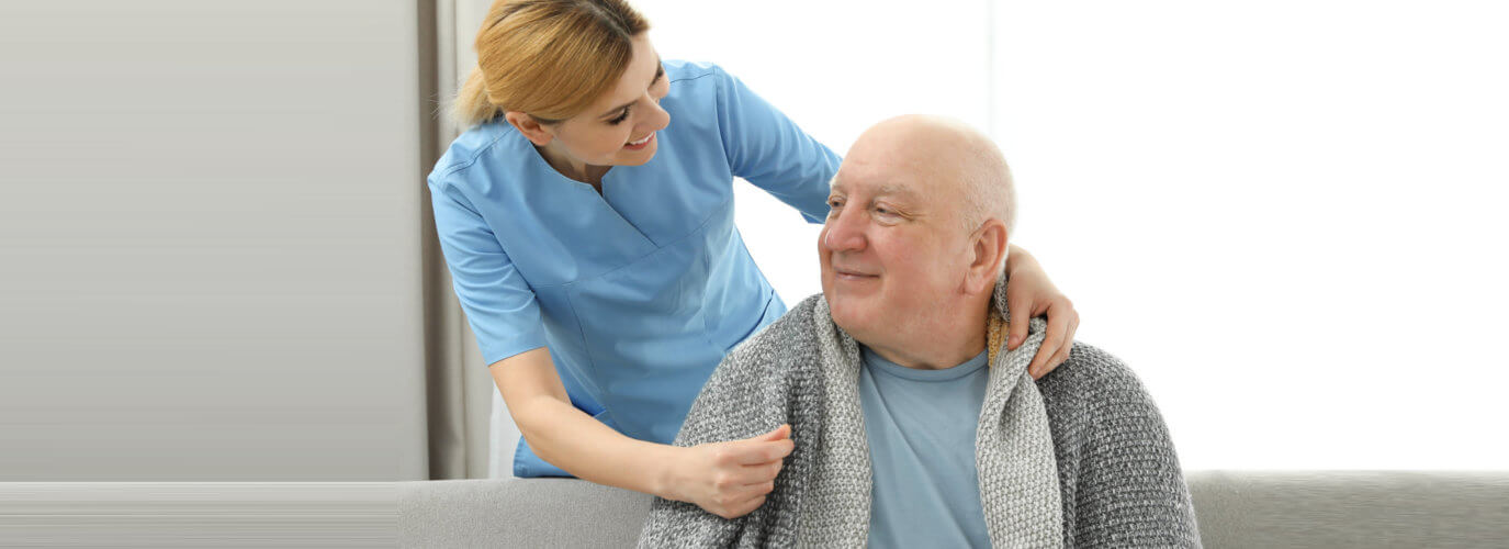 caregiver giving blanket to senior man